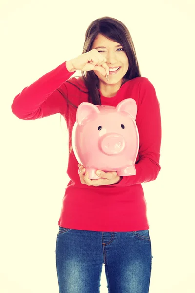 Glückliche Frau legt eine Münze ins Sparschwein. — Stockfoto