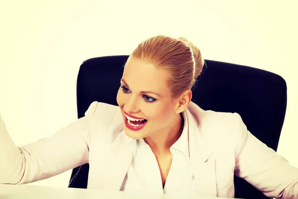 Szczęśliwa kobieta biznesu siedzi za biurkiem — Zdjęcie stockowe