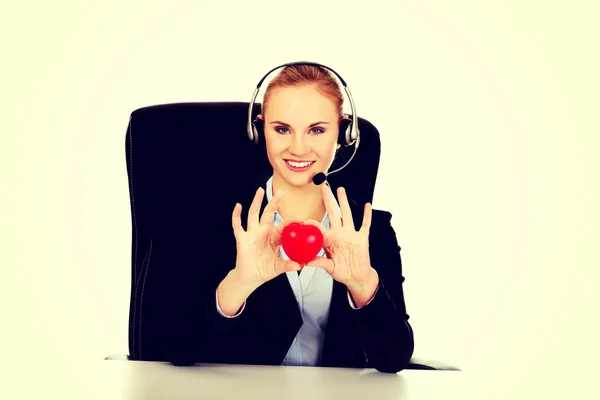 Feliz operador de teléfono mujer sosteniendo el juguete del corazón —  Fotos de Stock