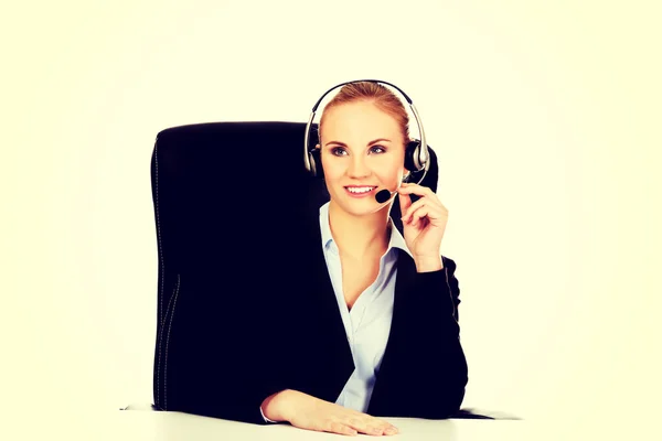 Lächelnder Telefonist mit Kopfhörer hinter dem Schreibtisch — Stockfoto