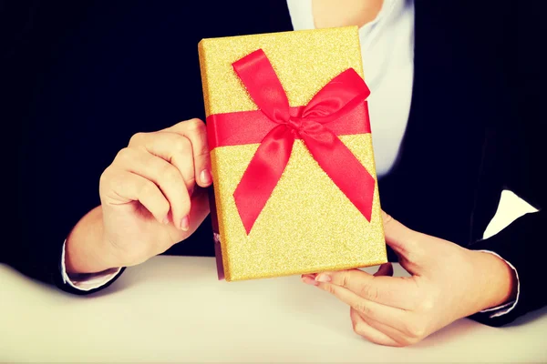 Mujer de negocios con caja de regalo sentada detrás del escritorio —  Fotos de Stock