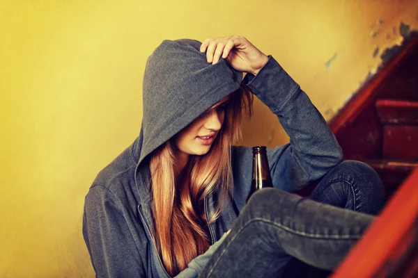 Teenage depressed woman sitting on the staircase and drinking a beer — Stock Photo, Image