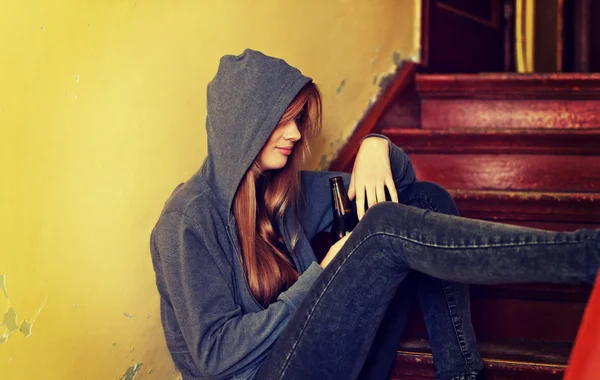 Teenage depressed woman sitting on the staircase and drinking a beer — Stock Photo, Image