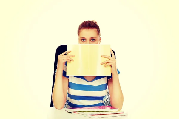 Tiener vrouw verbergt haar gezicht achter een notitieboekje — Stockfoto