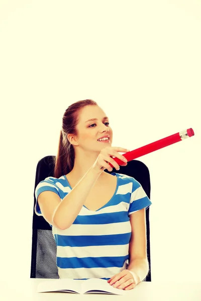 Teenage woman pointing for something with a huge pen — Stock Photo, Image