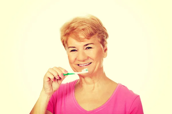 Sorridente donna anziana lavarsi i denti — Foto Stock