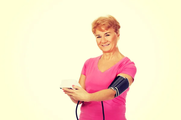 Senior woman measuring blood pressure with automatic manometer — Stock Photo, Image