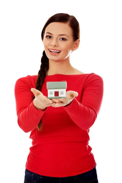 Усміхнена молода жінка тримає модель будинку — стокове фото