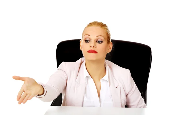 Mujer de negocios sentada detrás del escritorio y señalando la segunda silla — Foto de Stock