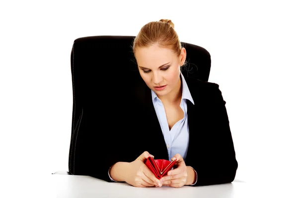 Mujer de negocios preocupada sentada detrás del escritorio con la cartera vacía — Foto de Stock