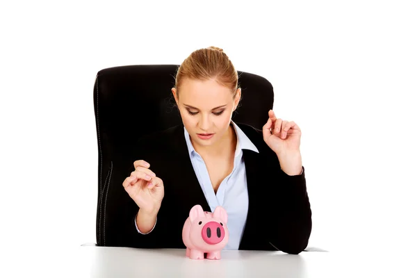 Glückliche Geschäftsfrau mit Sparschwein hinter dem Schreibtisch — Stockfoto