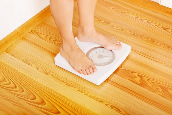 Senior woman standing on weight scale in living room — Stock Photo, Image