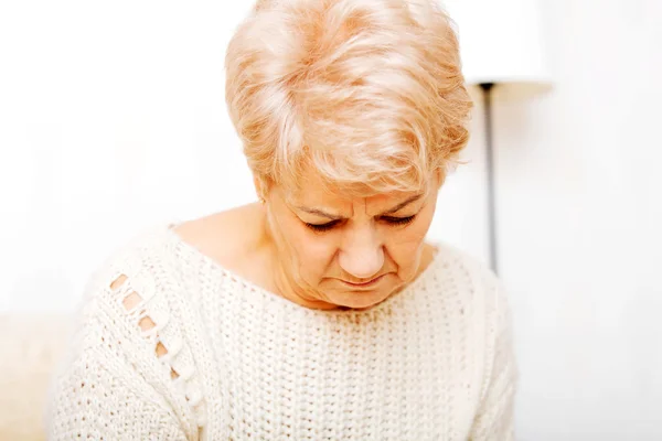 Elderly woman with depression sitting on couch — Stock Photo, Image