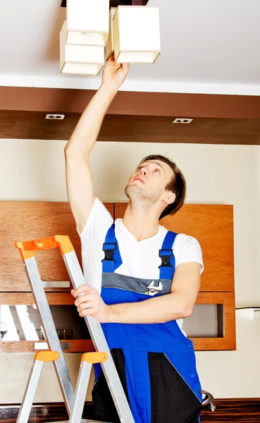 Young electrician working change a bulb at home — Stock Photo, Image