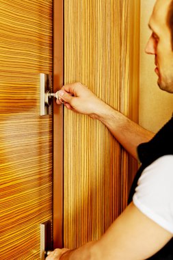 Genç adam eve dönüyor ya da evden çıkıyor.