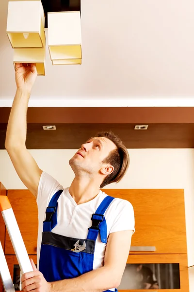 Jeune électricien travaillant changer une ampoule à la maison — Photo