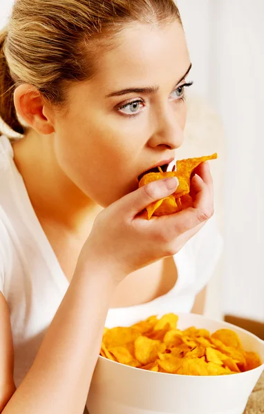 Giovane donna guardando la TV e mangiare patatine fritte — Foto Stock