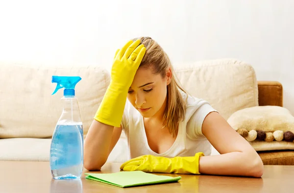 Müde junge Frau putzt Tisch in gelben Handschuhen — Stockfoto