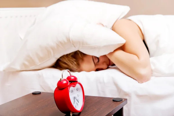 Jonge vrouw probeert te slapen als de wekker gaat — Stockfoto