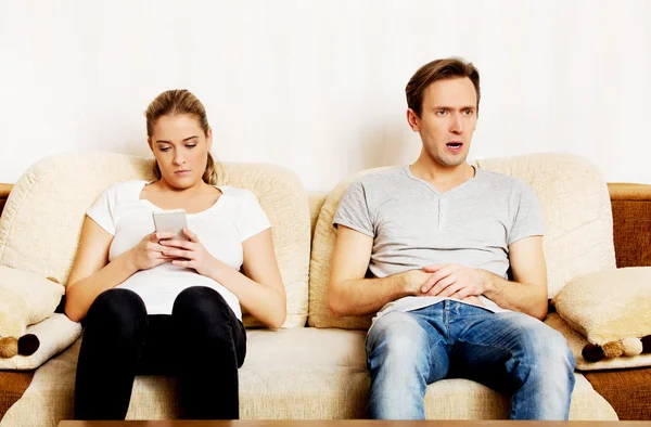 Casal em casa, homem assistindo tv mulher usando smartphone — Fotografia de Stock