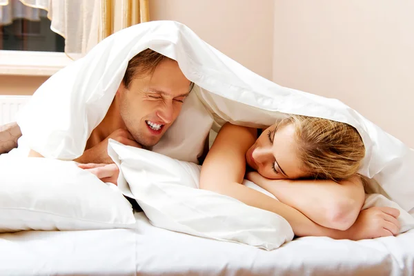 Jeune couple couché sur le lit sous la couette — Photo