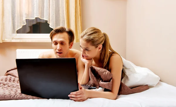 Casal jovem usando laptop na cama — Fotografia de Stock