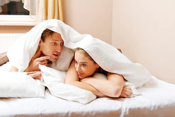 Jeune couple couché sur le lit sous la couette — Photo