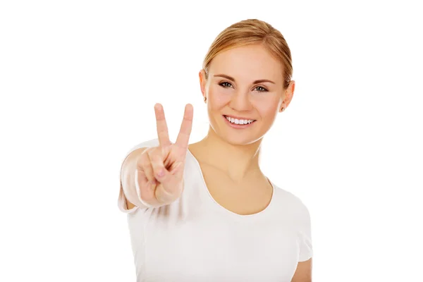 Jeune femme souriante montrant le signe de la victoire — Photo
