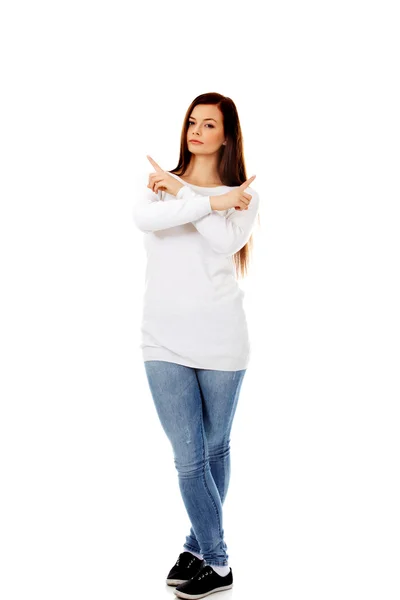 Förvirrad ung kvinna som pekar i två olika riktningar — Stockfoto