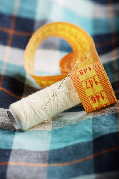 Checkered shirt thread needle and measure tape — Stock Photo, Image