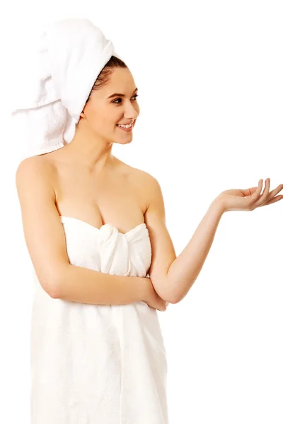 Mujer spa envuelta en toalla mostrando algo en la palma —  Fotos de Stock