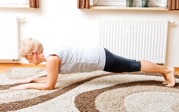 Seniorin macht Yoga im Wohnzimmer — Stockfoto