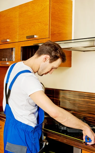 Young repair man measuring kitchen cabinet — Stock Photo, Image