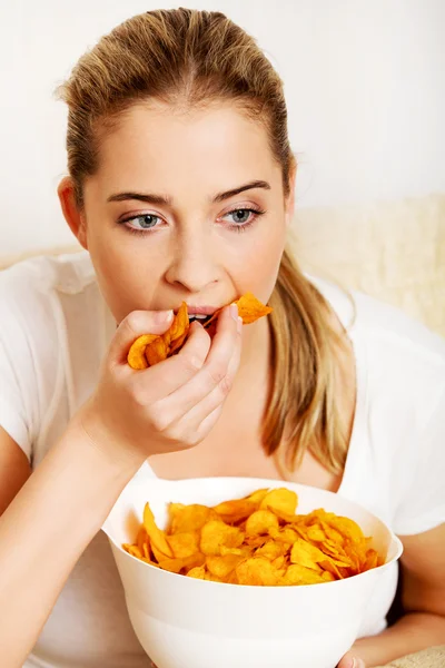 Giovane donna guardando la TV e mangiare patatine fritte — Foto Stock