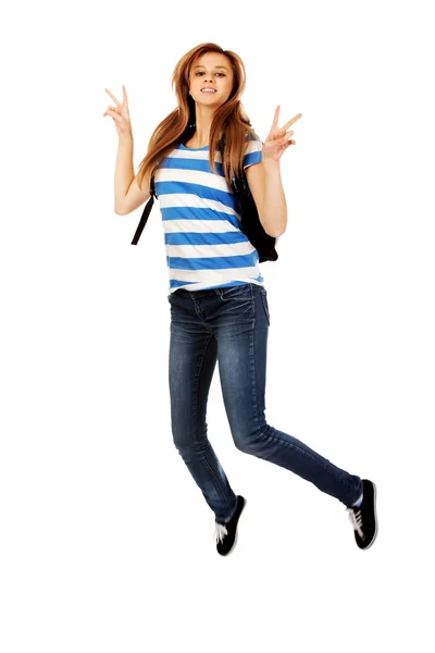 Tizenéves nő hátizsák jumping, és intett a béke — Stock Fotó