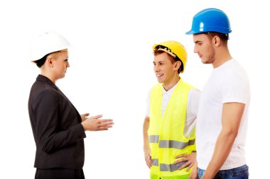 Kadın mühendis iki inşaatçıyla konuşuyor.