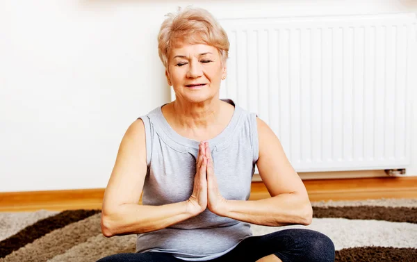 Senior vrouw doet yoga in de woonkamer — Stockfoto