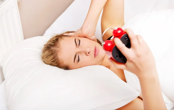 Молодая женщина пытается уснуть, когда звонит будильник — стоковое фото