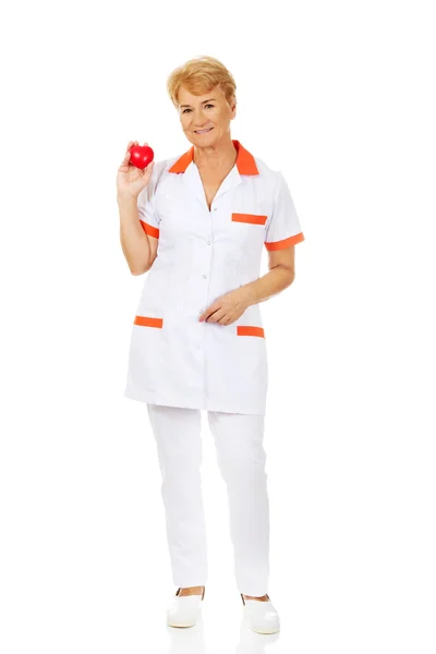 Sorrindo médico segurando coração de brinquedo vermelho — Fotografia de Stock