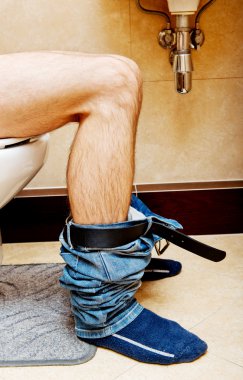 Adam klozet kapağında oturuyor.