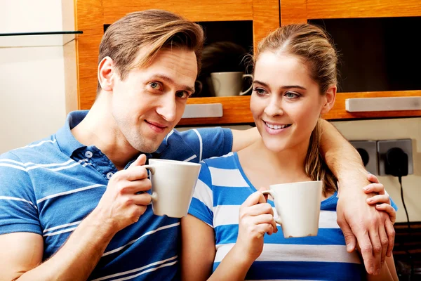 Young couple drinking coffee or tea in kitchen — Stock Photo, Image