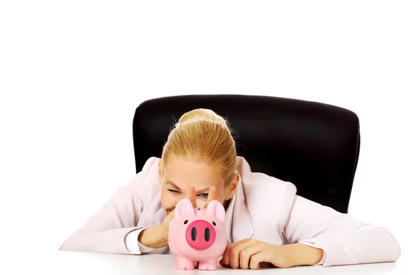 Happy affärskvinna med en piggybank bakom skrivbordet — Stockfoto