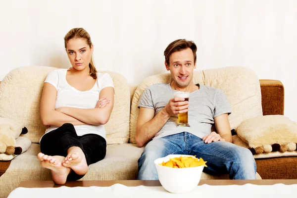 Mulher sentada entediada enquanto homem assistindo esportes — Fotografia de Stock