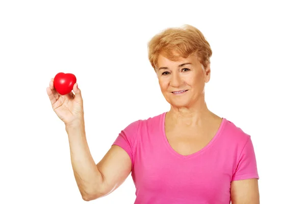 Old smiling woman holding red toy heart — Stock Photo, Image