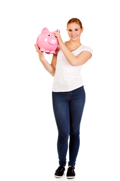 Glückliche junge Frau hält Sparschwein — Stockfoto