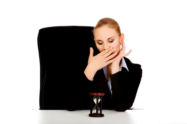 Yawning business woman with hourglass on the desk — Stock Photo, Image