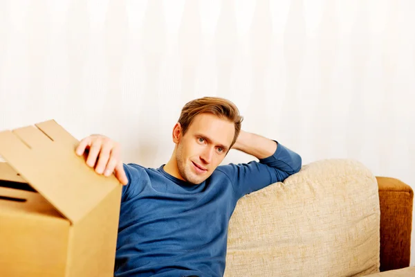 Tired man sitting on couch with cardboard boxes around — Stock Photo, Image