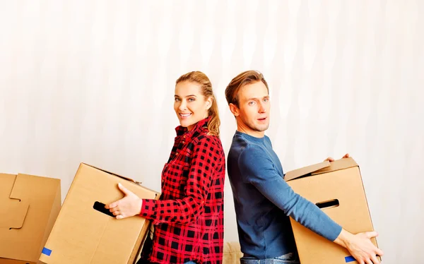 Casal feliz carregando caixas de papelão em nova casa — Fotografia de Stock