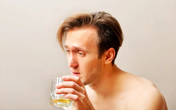 Hombre borracho sentado en la cama y bebiendo whisky — Foto de Stock