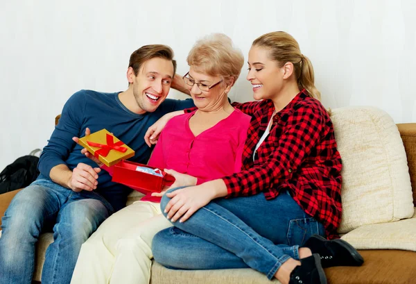 Lycklig familj - par med gammal kvinna som håller gift box och baby skor — Stockfoto